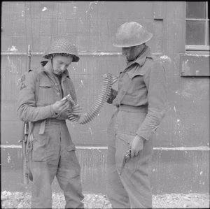 The British Army in the Normandy Campaign 1944 Soldiers from 3rd Division in Caen examine a belt of Hotchkiss machine-gun ammunition, 10 July 1944.