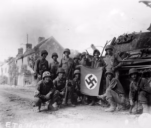 US soldiers celebrate with a captured German flag in front of a destroyed Panther tank. The group of infantrymen were left behind to "mop-up" in Chambois, France, last stronghold of the Germans in the Falaise Gap area