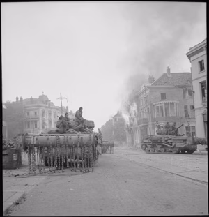 The British Army in North-west Europe 1944-45 Sherman Crab flail tanks in front of burning buildings in Arnhem, 14 April 1945.