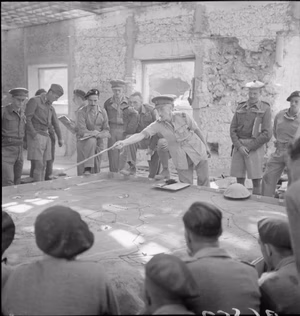 The Brigadier commanding the tanks in Tobruk instructing tank crews about the proposed operation. Beside him are various tank Commanders. He is using a sand table for demonstrating to the troops.