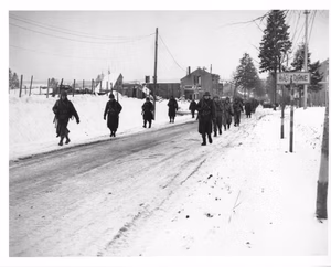 Scope and content: Original caption: Members of the 101st Airborne Division move out of Bastogne, Belgium, to drive the Germans who have besieged them for ten days, out of a neighboring town. This photo was taken while Bastogne was still under siege. 12/29/44.