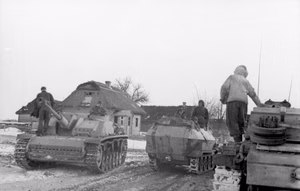 Rußland.- Sturmgeschütz III und Schützenpanzer auf Straße mit Schneematsch in Ortschaft, Frühjahr 1944; PK 670 — Russland
