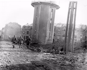Members of the 101st Airborne Division walk past dead comrades, killed during the Christmas Eve bombing of Bastogne, Belgium, the town in which this division was besieged for ten days. This photo was taken on Christmas Day, 1944.