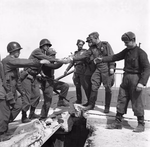 Cropped image derived from Begegnung der Alliierten in Torgau 1945, Infotafel am Bahnhof Torgau.jpg, a modern photograph (2022) of a publicly displayed information board at Torgau railway station, Germany. The information board includes a reproduction of the historic Elbe Day handshake photograph originally taken on 25 April 1945 by Associated Press photographer Allan Jackson. This file is a derivative work consisting solely of cropping. No claim of original authorship of the underlying 1945 photograph is made.