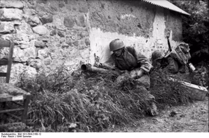 Frankreich.- Fallschirmjäger mit Raketenpanzerbüchse ("Ofenrohr" / "Panzerschreck") in Deckung hinter einem Feldstein-Haus in einer Ortschaft; PK Fs AOK — Frankreich