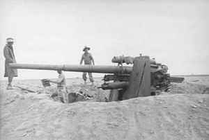 A German 88 mm FlaK 36 gun which had been used as a tank attack weapon near El Aqqaqir, Egypt. The whole crew were killed and were found buried alongside the gun. Allied Sherman and Crusader tanks can be seen on the skyline.