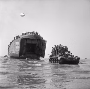 The British Army in the Normandy Campaign 1944 A Cromwell Mk IV tank of 4th County of London Yeomanry, 22nd Armoured Brigade, 7th Armoured Division, with infantry aboard, comes ashore from an LST, Gold area, 7 June 1944.