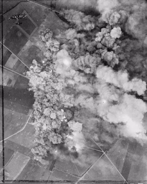 Royal Air Force Bomber Command, 1942-1945. An Avro Lancaster leaves the target area (top left), as smoke from exploding bombs smothers the village of Villers-Bocage, south-west of Caen, France. 942 aircraft of Bomber Command were despatched to bomb German-held positions, in support of the Second Army attack in the Normandy battle area (Operation GOODWOOD), on the morning of 18 July 1944.
