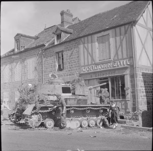 The British Army in the Normandy Campaign 1944 Troops and a civilian examine an abandoned German Mk IV tank with its gun protruding into a wrecked shop front in the village of Putanges, 20 August 1944.