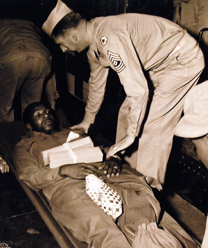80-G-41776: Two hundred and four American patients, taken from USS West Point (AP 23) at Newport News, Virginia, on May 30th, 1943. They came from North Africa along with 2,944 captive Axis soldiers. This African-American soldier is Private George William Curtis who was hurt at Oran on February 24th. Photographed May 30, 1943. U.S. Navy Photograph, now in the collections of the National Archives. (2016/05/10).