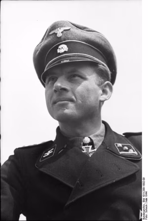 For documentary purposes the German Federal Archive often retained the original image captions , which may be erroneous, biased, obsolete or politically extreme . Scherl Bilderdienst: Kanalküste 15.5.44 Ein halbes Dutzend Tiger-Kommandanten. Sechs Kommandanten aus einer Kompanie der "SS-Panzer...Leibstandarte Adolf Hitler" vernicheten mit ihren Tigern nahezu 3 kampfstarke Panzerbrigaden. Der Kompaniechef - leuchtendes Vorbild. Obersturmführer Michael Wittmann steht mit seinen 117 Panzerabschüssen nicht nur an der Spitze seiner Kompanie, sonder ist einer der erfolgreichsten Panzerkommandanten überhaupt. Ausser ihm gingen noch weitere fünf Kommandanten aus seiner Kompanie hervor, die wegen besonderer Tapferkeit vor dem Feind mit dem Ritterkreuz ausgezeichnet wurden. Schon das allein spricht für den Geist, der in dieser Kompanie herrscht. Innerhalb von 14 Tagen wurde Obersturmführer Wittmann mit dem Ritterkreuz und dem Eichenlaub ausgezeichnet, vernichtete er doch in dieser Zeit weitere 28 russische Panzer, darunter grösstenteils T 34. Wenn man den Kompaniechef aus Vogelthal in der Oberpfalz, der mit seinen 30 Jahren kaum älter ist als die meisten seiner Kommandanten, im Gespräch mit seinen Männern beobachtet, fühlt man unwillkürlich die aus vielen Kämpfen geborene Kameradschaft heraus, die nötig ist, um aus Einzelkämpfern ein erfolgreiches Ganzes zu schaffen. Prop- Kp. 698, Bildberichter Scheck