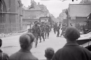The British Army in the Normandy Campaign 1944 Men of 46 (RM) Commando, 4th Special Service Brigade, entering the village of Douvres-la-Delivrande, 8 June 1944, watched by French civilians.