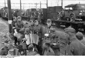 Frankreich-Süd, Ruffec.- Männer der Waffen-SS-Totenkopf-Division beim Verladen von Fahrzeugen auf Eisenbahnzug, Zuhörer beim Akkordeonspiel — Frankreich