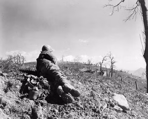 "3 Mar 45, 5/MM-45-3737. Fifth Army, M. della Vedetta, Italy. Prisoners are flushed out of house by assault platoon of "K" Co., 87th Mtn. Inf., 10th Mtn. Div., during the attack on Monte della Vedetta on the Poretta-Moderna Highway toward the Po Valley. The Germans had refused to surrender to troops occupying this knoll about 150-200 yards away. Photo by Baker. 196th Sig. Photo Co."