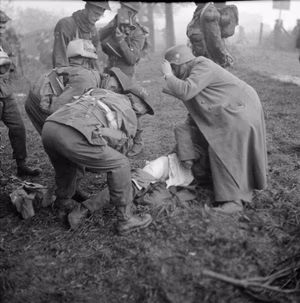 The British Army in North-west Europe 1944-45 A British medical officer and German POW attend to a casualty during the landings on Walcheren, 1 November 1944. Note the AFPU cameraman filming the incident.