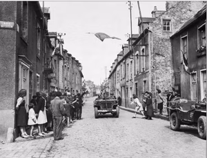 The French Tricolour floats over a street in Carentan, the first French town to be liberated by the Americans. French civilians wave their hands in welcome as men of the US 7th Corps pass through the streets after two days of bitter fighting The capture of Carentan materially strengthened the link between the two American beachheads.