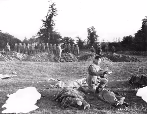 SC 190490 - U.S. Army Chaplain Francis L. Sampson of Sioux Falls, N.D., gives absolution to dead American paratroopers who were killed in action in Carentan, France.