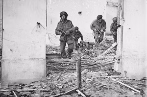 Four British paratroopers moving through a shell-damaged house in Oosterbeek to which they had retreated after being driven out of Arnhem.