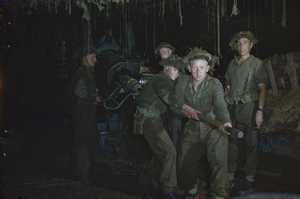 The British Army on the Caen Front in Normandy, July 1944 A gun crew of 53 Heavy Regiment, Royal Artillery loading a 155mm gun under camouflage netting. The 155mm gun was an American gun, often manned by British troops on the Normandy front.