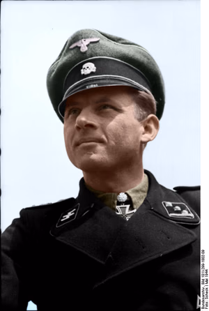 This is a retouched picture , which means that it has been digitally altered from its original version. Modifications: recolored . The original can be viewed here: Bundesarchiv Bild 101I-299-1802-09, Michael Wittmann.jpg : . Modifications made by Ruffneck'88 . .mw-parser-output table.commons-file-information-table,.mw-parser-output .fileinfotpl-type-information,.mw-parser-output .fileinfotpl-type-artwork{border:1px solid var(--border-color-base,#a2a9b1);background-color:var(--background-color-interactive-subtle,#f8f9fa);padding:5px;font-size:95%;border-spacing:2px;box-sizing:border-box;margin:0;width:100%;color:inherit}.mw-parser-output table.commons-file-information-table>tbody>tr,.mw-parser-output .fileinfotpl-type-information>tbody>tr,.mw-parser-output .fileinfotpl-type-artwork>tbody>tr{vertical-align:top}.mw-parser-output table.commons-file-information-table>tbody>tr>td,.mw-parser-output table.commons-file-information-table>tbody>tr>th,.mw-parser-output .fileinfotpl-type-information>tbody>tr>td,.mw-parser-output .fileinfotpl-type-information>tbody>tr>th,.mw-parser-output .fileinfotpl-type-artwork>tbody>tr>td,.mw-parser-output .fileinfotpl-type-artwork>tbody>tr>th{padding:4px}.mw-parser-output .fileinfo-paramfield{background:#ccf;text-align:right;padding-right:0.4em;width:15%;font-weight:bold;color:inherit}.mw-parser-output .commons-file-information-table+table.commons-file-information-table,.mw-parser-output .commons-file-information-table+div.commons-file-information-table>table{border-top:0;padding-top:0;margin-top:-8px}@media only screen and (max-width:719px){.mw-parser-output table.commons-file-information-table,.mw-parser-output .commons-file-information-table .fileinfotpl-type-information,.mw-parser-output .commons-file-information-table .fileinfotpl-type-artwork{border-spacing:0;padding:0;word-break:break-word;width:100%!important}.mw-parser-output .commons-file-information-table>tbody,.mw-parser-output .fileinfotpl-type-information>tbody,.mw-parser-output .fileinfotpl-type-artwork>tbody{display:block}.mw-parser-output .commons-file-information-table>tbody>tr>td,.mw-parser-output .commons-file-information-table>tbody>tr>th,.mw-parser-output .fileinfotpl-type-information>tbody>tr>td,.mw-parser-output .fileinfotpl-type-information>tbody>tr>th,.mw-parser-output .fileinfotpl-type-artwork>tbody>tr>td,.mw-parser-output .fileinfotpl-type-artwork>tbody>tr>th{padding:0.2em 0.4em;text-align:left;text-align:start}.mw-parser-output .commons-file-information-table>tbody>tr,.mw-parser-output .fileinfotpl-type-information>tbody>tr,.mw-parser-output .fileinfotpl-type-artwork>tbody>tr{display:flex;flex-direction:column}.mw-parser-output .commons-file-information-table+table.commons-file-information-table,.mw-parser-output .commons-file-information-table+div.commons-file-information-table>table{margin-top:-1px}.mw-parser-output table .fileinfo-paramfield{box-sizing:border-box;flex:1 0 100%;width:100%}}.mw-parser-output table.commons-file-information-table,.mw-parser-output .fileinfotpl-type-information,.mw-parser-output .fileinfotpl-type-artwork,.mw-parser-output .fileinfo-paramfield{color:var(--color-base,#202122)}html.skin-theme-clientpref-night .mw-parser-output .fileinfo-paramfield{background:#2a2a5c;color:white}html.skin-theme-clientpref-night .mw-parser-output .fileinfotpl-type-artwork tbody>tr>th[style*="#ccf"]{background-color:#2a2a5c!important;color:white}@media screen and (prefers-color-scheme:dark){html.skin-theme-clientpref-os .mw-parser-output .fileinfo-paramfield{background:#2a2a5c;color:white}html.skin-theme-clientpref-os .mw-parser-output .fileinfotpl-type-artwork tbody>tr>th[style*="#ccf"]{background-color:#2a2a5c!important;color:white}} Michael Wittmann ( ) Photographer Scheck Archive description InfoField Description provided by the archive when the original description is incomplete or wrong. You can help by reporting errors and typos at Commons:Bundesarchiv/Error reports . Nordfrankreich.- Obersturmführer Michael Wittmann (Porträt) mit Eichenlaub zum Ritterkreuz (verliehen am 30. Januar 1944); PK 698 Title Michael Wittmann Original caption For documentary purposes the German Federal Archive often retained the original image captions , which may be erroneous, biased, obsolete or politically extreme . Scherl Bilderdienst: Kanalküste 15.5.44 Ein halbes Dutzend Tiger-Kommandanten. Sechs Kommandanten aus einer Kompanie der "SS-Panzer...Leibstandarte Adolf Hitler" vernicheten mit ihren Tigern nahezu 3 kampfstarke Panzerbrigaden. Der Kompaniechef - leuchtendes Vorbild. Obersturmführer Michael Wittmann steht mit seinen 117 Panzerabschüssen nicht nur an der Spitze seiner Kompanie, sonder ist einer der erfolgreichsten Panzerkommandanten überhaupt. Ausser ihm gingen noch weitere fünf Kommandanten aus seiner Kompanie hervor, die wegen besonderer Tapferkeit vor dem Feind mit dem Ritterkreuz ausgezeichnet wurden. Schon das allein spricht für den Geist, der in dieser Kompanie herrscht. Innerhalb von 14 Tagen wurde Obersturmführer Wittmann mit dem Ritterkreuz und dem Eichenlaub ausgezeichnet, vernichtete er doch in dieser Zeit weitere 28 russische Panzer, darunter grösstenteils T 34. Wenn man den Kompaniechef aus Vogelthal in der Oberpfalz, der mit seinen 30 Jahren kaum älter ist als die meisten seiner Kommandanten, im Gespräch mit seinen Männern beobachtet, fühlt man unwillkürlich die aus vielen Kämpfen geborene Kameradschaft heraus, die nötig ist, um aus Einzelkämpfern ein erfolgreiches Ganzes zu schaffen. Prop- Kp. 698, Bildberichter Scheck Depicted people Wittmann, Michael : SS-Hauptsturmführer, Ritterkreuz, Waffen-SS, Deutschland ( GND 119260573 ) Date May 1944 date QS:P571,+1944-05-00T00:00:00Z/10 Collection German Federal Archives Native name Das Bundesarchiv Parent institution Federal Government Commissioner for Culture and Media Location Koblenz (headquarters) Coordinates 50° 20′ 32.71″ N, 7° 34′ 21.22″ E Established 1946 Website www.bundesarchiv.de Authority file : Q685753 VIAF : 137346469 ISNI : 0000000405552728 LCCN : n92025526 NLA : 36455393 OSM : 1844909 WorldCat institution QS:P195,Q685753 Current location Propagandakompanien der Wehrmacht - Heer und Luftwaffe (Bild 101 I) Accession number Bild 101I-299-1802-09 Source This image was provided to Wikimedia Commons by the German Federal Archive (Deutsches Bundesarchiv) as part of a cooperation project . The German Federal Archive guarantees an authentic representation only using the originals (negative and/or positive), resp. the digitalization of the originals as provided by the Digital Image Archive . Other versions This image has an extracted file : Bundesarchiv Bild 101I-299-1802-09, Michael Wittmann Recolored (cropped).png .