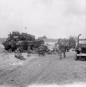 D-day - British Forces during the Invasion of Normandy 6 June 1944 Troops of 3rd Division on Queen beach, Sword area, 6 June 1944. On the left, medics attend to wounded next to a disabled Churchill AVRE from 5th Assault Regiment, Royal Engineers. The AVRE is a SBG bridge carrier, and has already laid its bridge.