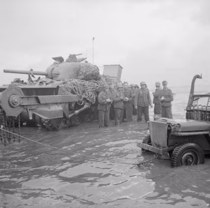 D-day - British Forces during the Invasion of Normandy 6 June 1944 A group of German prisoners standing in the water next to a disabled Sherman Crab flail tank watch as a jeep is towed from the sea, Queen beach, Sword area, 6 June 1944.