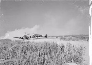 Royal Air Force- 2nd Tactical Air Force, 1943-1945. A Supermarine Spitfire Mark IX raises the dust as it taxies past a Hawker Typhoon Mark IB of No. 181 Squadron RAF, at an advanced landing ground - probably B2/Bazenville - in Normandy. The Spitfire is fitted with a 45-gallon 'slipper' fuel tank.