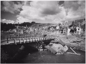 An overturned German tank lies in a shallow stream alongside a rebuilt bridge in war ravaged Houffalizo, Belgium. NARA 196224