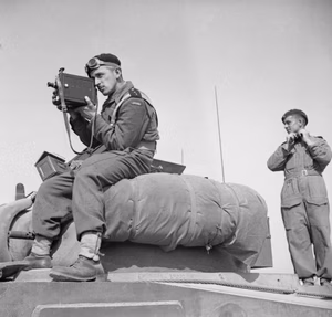 The 1st Polish Armoured Division in the Normandy Campaign 1944 Cameramen in uniform: 2nd Lieutenant Jerzy Januszajtis, a Polish Army Film Unit cameraman, films from the top of a Sherman tank of the 1st Polish Armoured Division tank during Operation 'Totalise', south of Caen, Normandy on 8 August 1944. He is using a De Vry camera fitted with a sling.