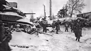 Members of the 117th Infantry Regiment, 30th Infantry Division, move past a destroyed American M5 "Stuart" tank on their march to capture the town of St. Vith at the close of the Battle of the Bulge. St. Vith was largely destroyed during the ground battle and subsequent air attack. American forces retook the town on 23 January 1945.