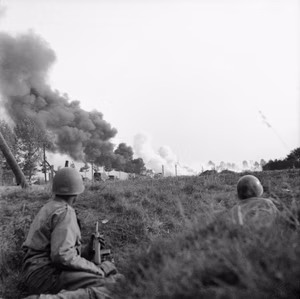A convoy of Allied lorries under enemy artillery and mortar fire on the road between Son and Eindhoven, Holland, 20 September 1944. In the foreground American paratroopers shelter in a ditch. A convoy of lorries under enemy artillery and mortar fire on the road between Son and Eindhoven, 20 September 1944. In the foreground American paratroopers shelter in a ditch.