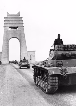 Panzer Mk IIIs and Mk IIs cross under the marble arch at Sirte as they reinforce the Italians in the western desert.