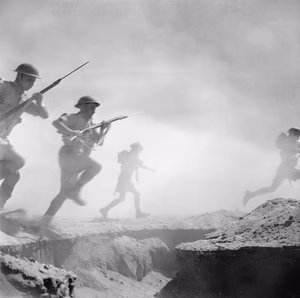 El Alamein 1942: British infantry advances through the dust and smoke of the battle. Sergeant Len Chetwyn had a focus on creating and recording re-enactments of military scenes behind the front lines rather than recording live activities on the front lines.