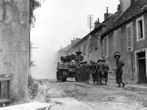 The Sherman tank "Bomb" of the Sherbrooke Fusiliers hunts snipers with troops of the Mont Royal Regiment in Falaise, August 17, 1944.