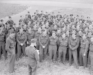 Royal Air Force 1939-1945- Bomber Command Watched by the CO, Wing Commander D A Gardner (left), aircrew of No 166 Squadron at Kirmington, Lincolnshire, gather on 20 July 1944 to hear the Adjutant, Flight Lieutenant F C Tigh, read out a congratulatory message from Field Marshal Montgomery, thanking the bomber crews for their efforts supporting the British Second Army's armoured offensive in Normandy, Operation 'Goodwood'.