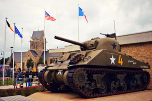 This M4A1(76)W HVSS Sherman Tank (sometimes called the M4A1E8 Easy 8) is part of the WW2 D-Day landings display at the US Airborne Forces Museum in Saint-Mere-Eglise. The Museum is built on the site of the house that was bombed and burnt down on D-Day that is seen on the film the Longest Day. It was the light from this fire that enabled the Germans stationed in the town to shot so many paratroopers as they were blown off course and landed in Saint-Mere-Eglise. The problem is that this version of the Sherman tank never took part in the D-Day landings on 6th June 1944 or the battle for Normandy. The first 'Easy Eight' M4A1(76)W HVSS Sherman tanks only arrived in Europe in December 1944. Photo of misc. World War II militaria in Airborne Museum , a French museum dedicated to the memory of paratroopers of the 82nd and 101st Airborne Divisions of the United States Army who parachuted into Normandy on the night of June 5–6, 1944. Sainte-Mère-Église, Arrondissement de Cherbourg, Normandy. Summer holidays in France, August 2019