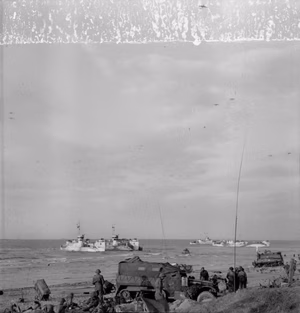 D-day - British Forces during the Invasion of Normandy 6 June 1944 Glider trains of 6th Airlanding Brigade, 6th Airborne Division, flying over vehicles and landing craft on Queen beach in Sword area, on the evening of 6 June 1944. An HQ half-track can be seen in the foreground, with a Sherman BARV (Beach Armoured Recovery Vehicle) at work in the distance.