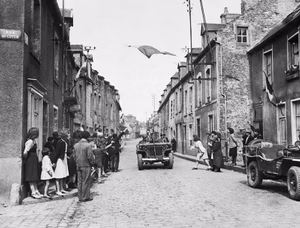 THE ALLIED CAMPAIGN IN NORTH-WEST EUROPE, 6 JUNE 1944 - 7 MAY 1945 The Battle for Normandy: The French Tricolour floats over a street in Carentan, the first French town to be liberated by the Americans. French civilians wave their hands in welcome as men of the US 7th Corps pass through the streets after two days of bitter fighting The capture of Carentan materially strengthened the link between the two American beachheads.