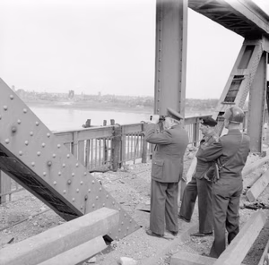 The British Army in North-west Europe 1944-45- the Prime Minister Crosses the Rhine Prime Minister, Field Marshal Montgomery and General Simpson, on blown bridge at Wesel. Town in background. While on bridge enemy were shelling river.