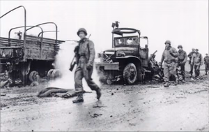 American GIs pass trucks destroyed by German artillery on March 11, 1945 near Remagen, Germany.
