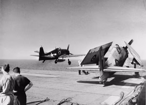 A U.S. Navy Grumman F6F Hellcat assigned to VGF-1 aboard USS Tulagi (CVE-72) launching from the Royal Navy escort carrier HMS Emperor (D98). One of the carrier's own Hellcat s of 800 Naval Air Squadron, Fleet Air Arm, is seen parked forward during the invasion of southern France.