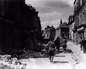 Des soldats américains patrouillent dans une rue de Carentan.