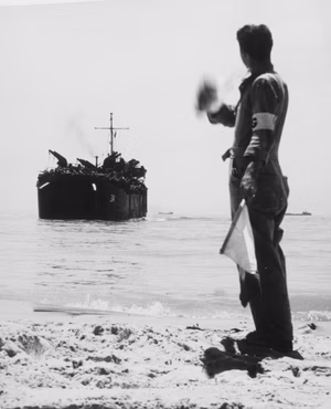 Beach group signalman directs USS LST-314 to her landing place on a Sicily beach.
