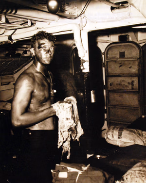 80-G-54604: Invasion of Sicily, September 1943. USS Rowan (DD 405). Three survivors smeared with oil and blood awaiting medical attention following the sinking of their ship in Italian waters as a result of an underwater explosion. Photograph released September 25, 1943. U.S. Navy Photograph, now in the collections of the National Archives. (2016/11/25).
