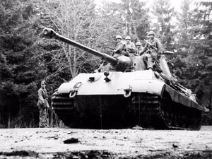 A German soldier stands to the side of a Tiger II tank loaded with paratroopers at the Kaiserbaracke crossroads in Belgium, in December 1944. The tank was on its way to Ligneuville, Belgium.