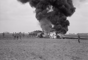 The British Army in North-west Europe 1944-45 An American C-47 aircraft, hit by flak returning from the Market-Garden drop, burns after crash-landing into a knocked-out German Jagdpanther in a field near Gheel in Belgium, 17 September 1944.