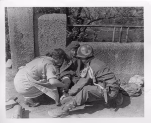 German nurse assists a Ninth U.S. Army medic treat a wounded German SS trooper, [sic] captured during the battle for Unna, Germany. Unna is located in the industrial Ruhr valley pocket and was defended by a large number of German SS troops before its capture by 9th U.S. Army troops. 11 April, 1945. Note: The German soldier in the photo appears to be a member of the Heer, not the SS as the original caption states.