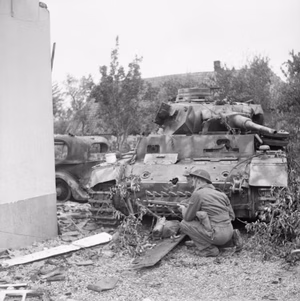 The British Army in North-west Europe 1944-45 A soldier crouches near a knocked-out German PzKpfw III tank in Oosterhout near Nijmegen, 27 September 1944.