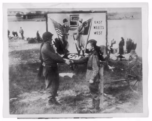 Pfc. Frank Huff (left), of Washington, Va., said to be one of the first four Americans to make contact with the Russians at Torgau, 58 miles southwest of Berlin, April 25, shakes hands with a Russian soldier to symbolize the meeting of the two armies at the Elbe River, before a poster depicting the event — Soldiers--Germany--Torgau--1940-1950. Fraternization--Germany--Torgau--1940-1950. Billboards--Germany--Torgau--1940-1950. World War, 1939-1945,--Military personnel--Germany--Torgau. World War, 1939-1945,--Armistices--Germany--Torgau. Photographic prints--1940-1950. Publicity photographs--1940-1950. Radio photographs--1940-1950. — 1945.