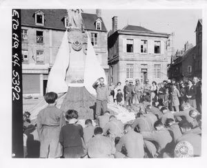 The monument, draped with parachutes, is a World War 1 tribute from the citizens of Carentan to its soldier dead. Photographer: Collier. 19 June, 1944. Photo Source: U.S. National Archives. Digitized by Signal Corps Archive.